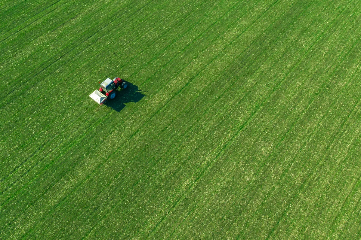 Aerial view of a tractor working in a green field